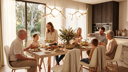 A multi-generational family gathered for a dinner party around a large, light-toned rectangular dining table, seated on matching modern chairs with white, curved shells and light-toned legs, set in a spacious, light-filled dining area.