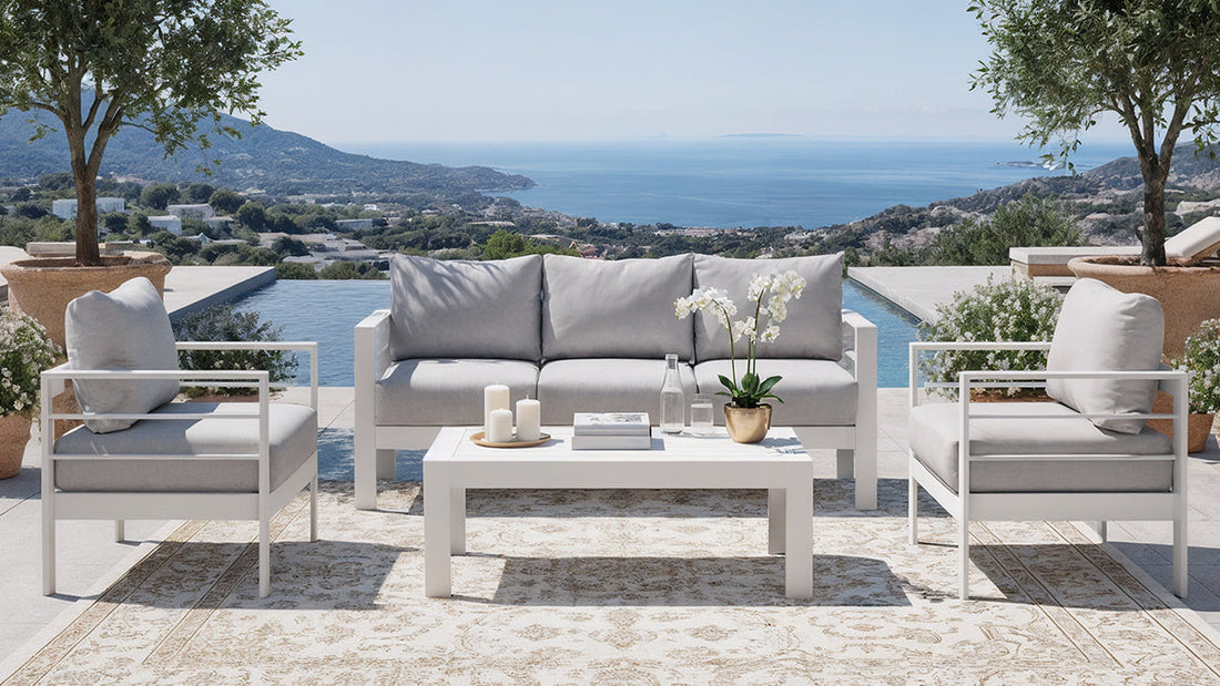 Luxo Bayo 6-Seater Aluminium Outdoor Set in White & Grey, featuring a plush cushioned sofa and armchairs around a low table, elegantly arranged in a scenic outdoor setting with rolling hills and sea views.