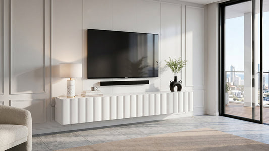 Matte white fluted floating TV unit under wall-mounted television in a bright living room.