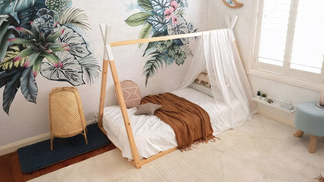 Bohemian gender-neutral twin kids bedroom featuring a wooden teepee bed frame, botanical wall mural, and neutral-toned decor for shared spaces.