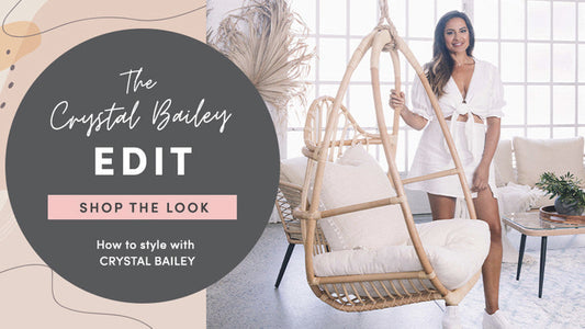 Crystal Bailey standing next to a rattan hanging chair in a stylish alfresco room, demonstrating how to style the space to achieve a beautiful look.