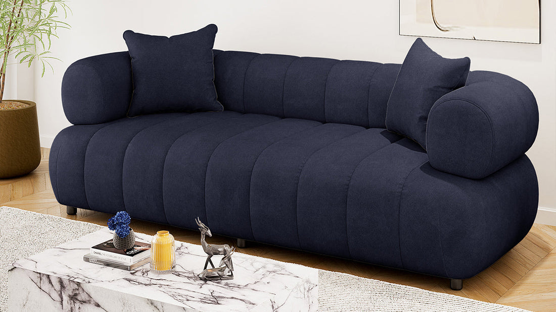 Elegant, low-profile navy blue channel-tufted sofa with a large marble block coffee table