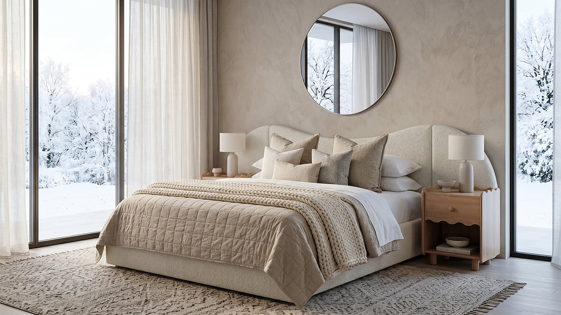 Neutral bedroom with upholstered bed, round mirror and snowy window view