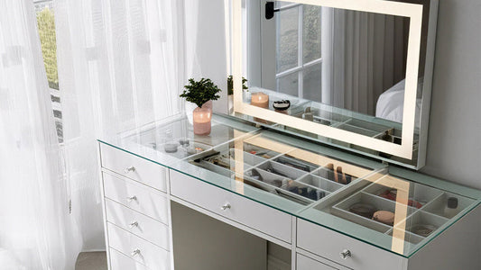  A close-up shot of a modern, white dressing table with a clear glass top, showcasing organized drawers beneath. The table has multiple storage drawers with crystal-like knobs. 