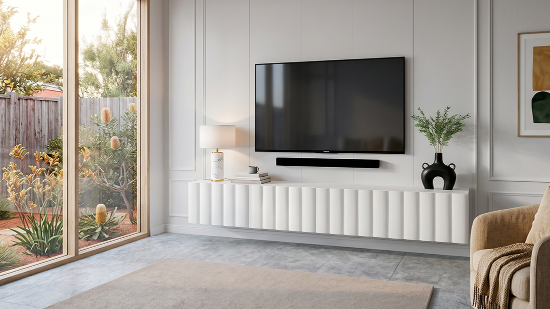 Minimalist wall-mounted entertainment console under a large television overlooking a bright backyard view.