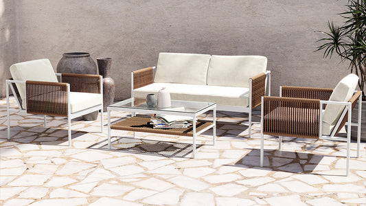 Brujas & Culion Outdoor Sofa Set features a white-framed sofa with cream cushions, matching armchairs, and a glass coffee table on a stone patio, creating a modern-rustic outdoor lounge.