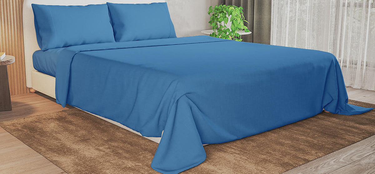 Modern bedroom with a low-profile platform bed featuring blue pillows and bedspread, wood-slat accent wall, sheer curtains, bedside table with books, and a potted plant on a side table.