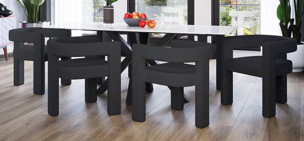 Modern dining-room with a white stone-top table and dark metal legs, surrounded by six black upholstered chairs. Table features apples and a potted plant; garden view through large windows.