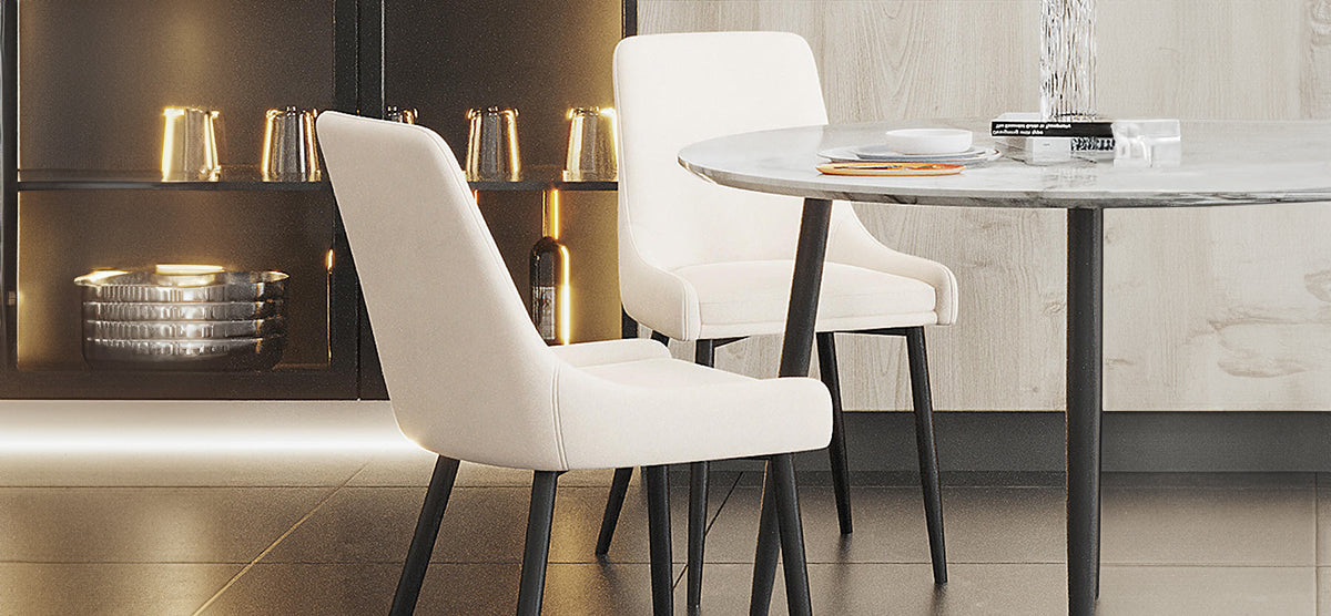 A modern dining nook featuring two white-upholstered chairs, a round marble-top table with black metal base, and a backlit shelving unit with metal mugs and bowls.