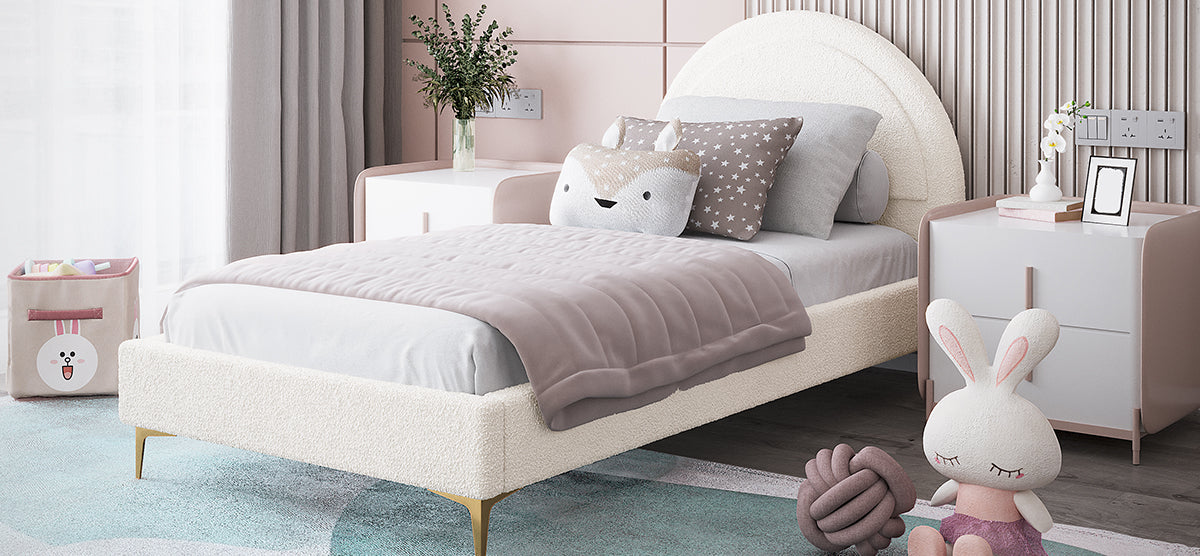 Children's bedroom corner with a cream bouclé bed, mauve quilt, decorative pillows, pastel bedside cabinet with orchids, plush bunny, and cartoon rabbit storage basket.