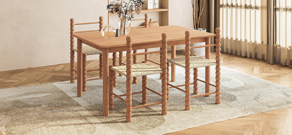 Minimalist dining area with a light-wood rectangular table and four chairs featuring bead-style turned legs and woven seats. Glass vases with dried flowers adorn the table.