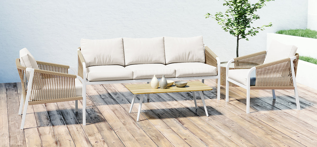 Modern outdoor seating area on a wooden patio with a three-seat sofa and two armchairs featuring light cushions and rope-wrapped sides. A light wood coffee table holds three decorative vessels.