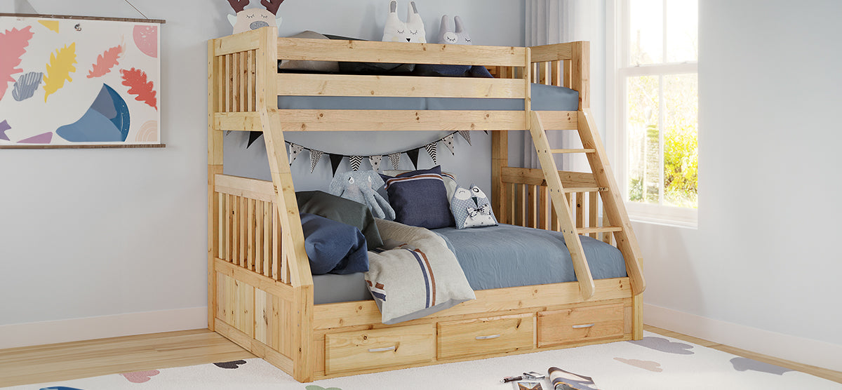 Children’s bedroom corner with a natural‐pine twin-over-full bunk bed, featuring a slanted ladder, safety rails, built-in drawers, blueish bedding, stuffed animals, and a pennant banner.
