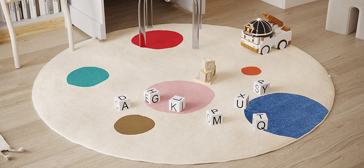 Children’s play corner with a round cream rug featuring colorful circles, scattered white wooden letter blocks, a small toy truck, and a low shelf with books.