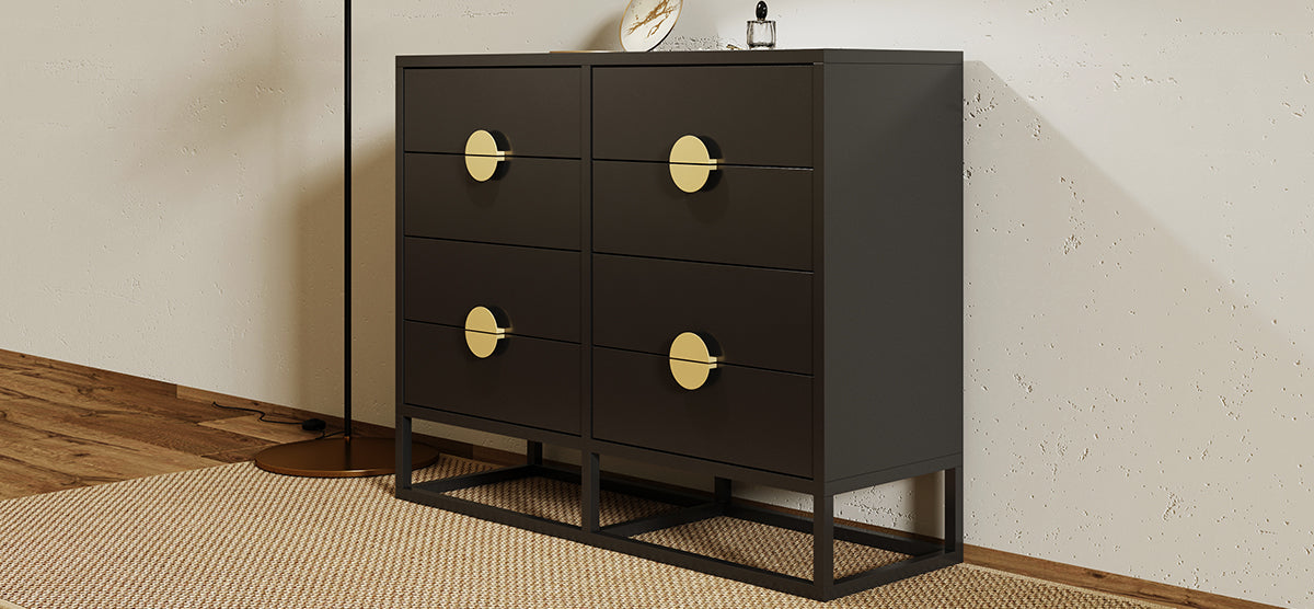 Modern six-drawer chest in matte black with large gold-tone knobs, on a black metal base, accompanied by a slim black floor lamp and a low-pile woven rug.