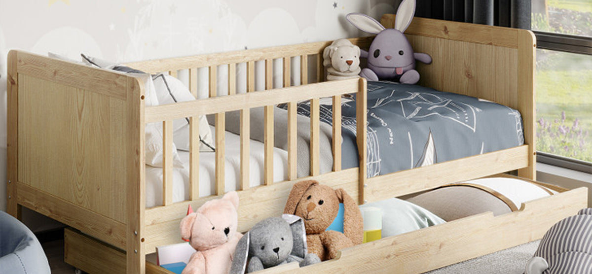 Children’s bed in light wood with low rail, featuring blue-gray bedding with line motifs. Includes plush toys, pull-out trundle with more stuffed animals.