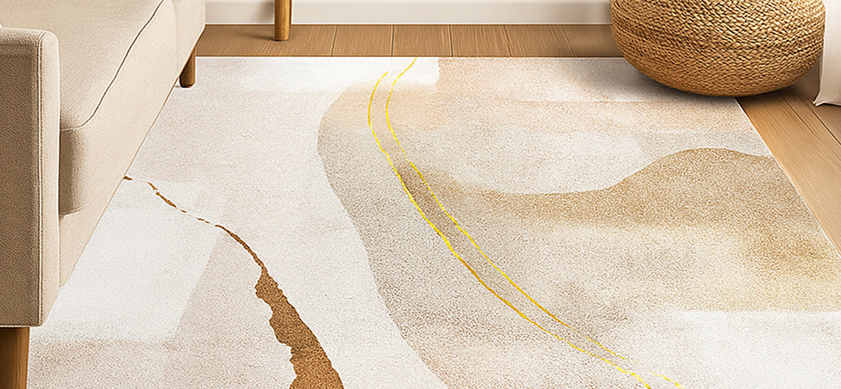 Close-up of a light-colored living room floor featuring a large area rug with abstract swirls in beige and gold. Visible are a sofa leg and a rattan pouf.