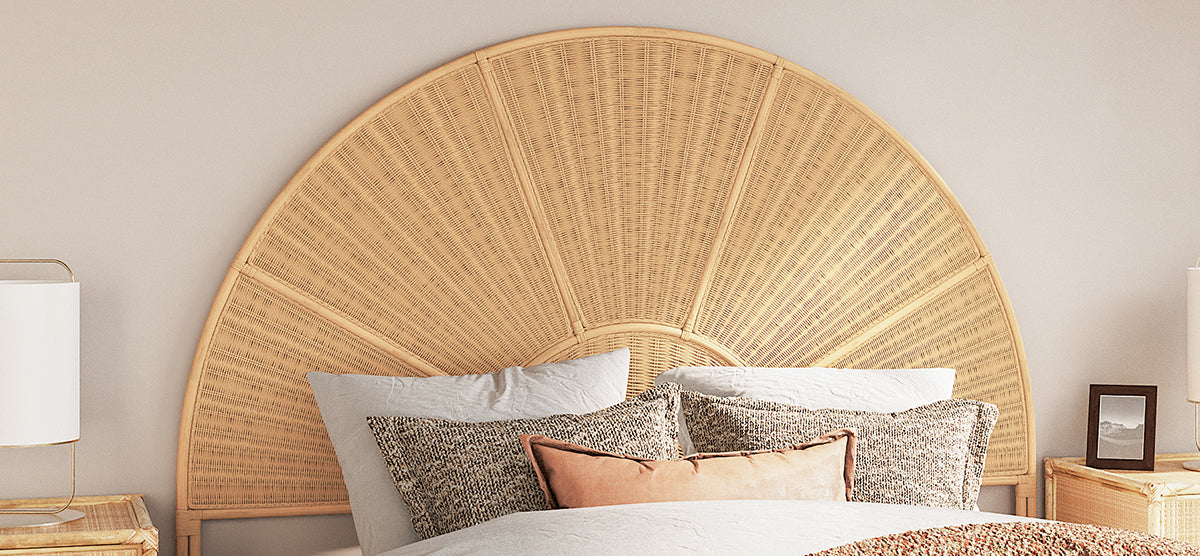 Boho-inspired bedroom with a semi-circular woven rattan headboard, neutral-toned pillows, light duvet, matching nightstands, white-shaded lamps, and a small framed photo on the right nightstand.