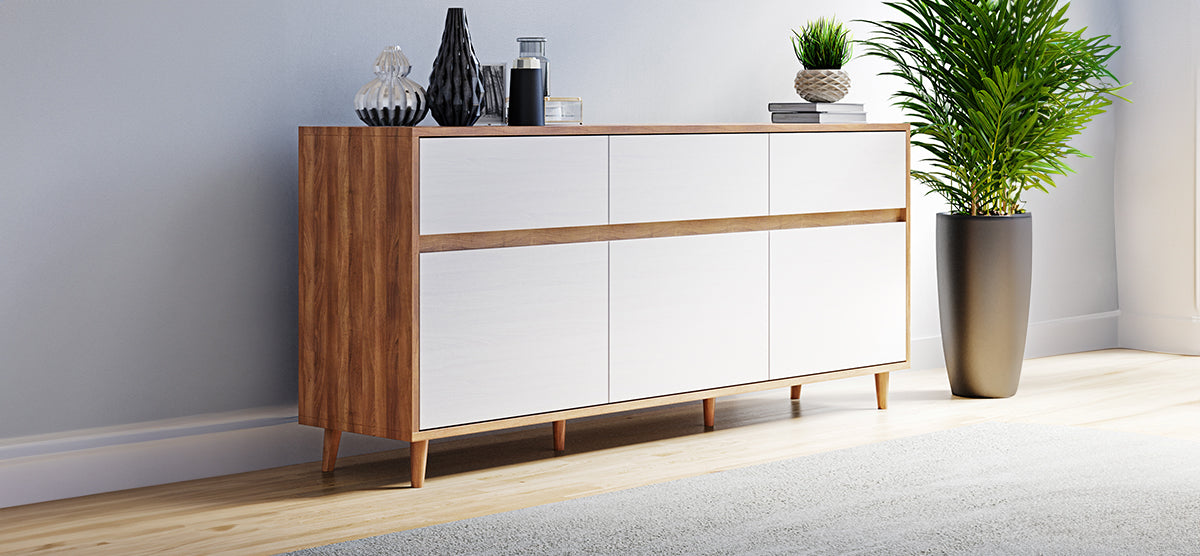 Mid-century-style sideboard with warm wood frame and six white doors, topped with decorative vases, books, and a potted plant; adjacent to a tall leafy plant.