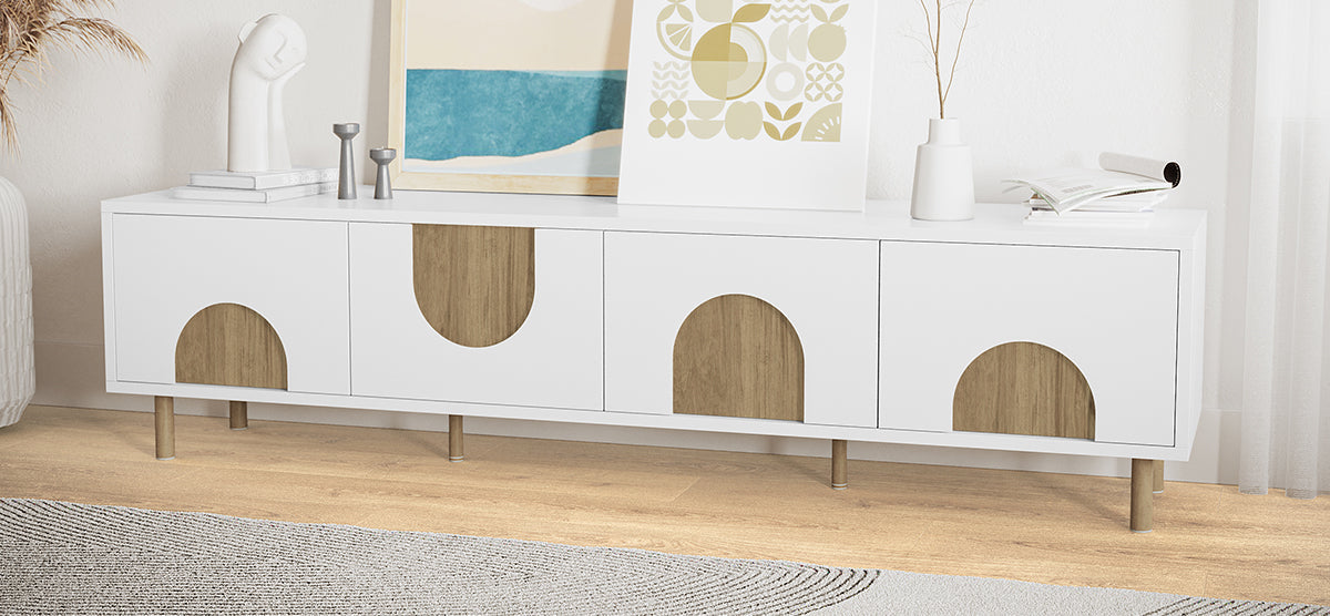 White storage console with semicircular wood-grain handles, topped with abstract prints, a sculptural bust, candleholders, an open magazine, and a vase with dried stems. Scandinavian minimalist style.