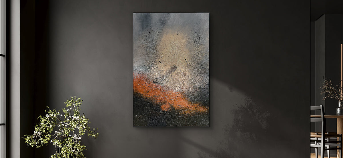 Abstract painting on dark-gray wall with muted grays, beiges, rusty orange, and charcoal tones; flanked by a green potted plant and part of a dining set.