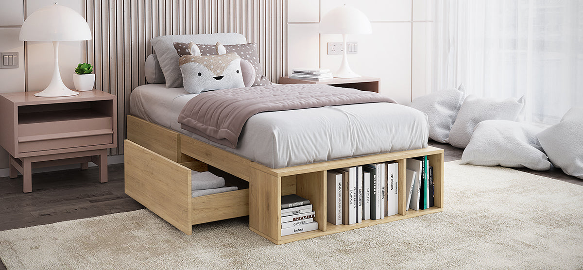 Modern bedroom corner with a wooden single bed featuring storage, blush-pink bedside tables with dome lamps, a potted succulent, and a floor-to-ceiling window with floor cushions.