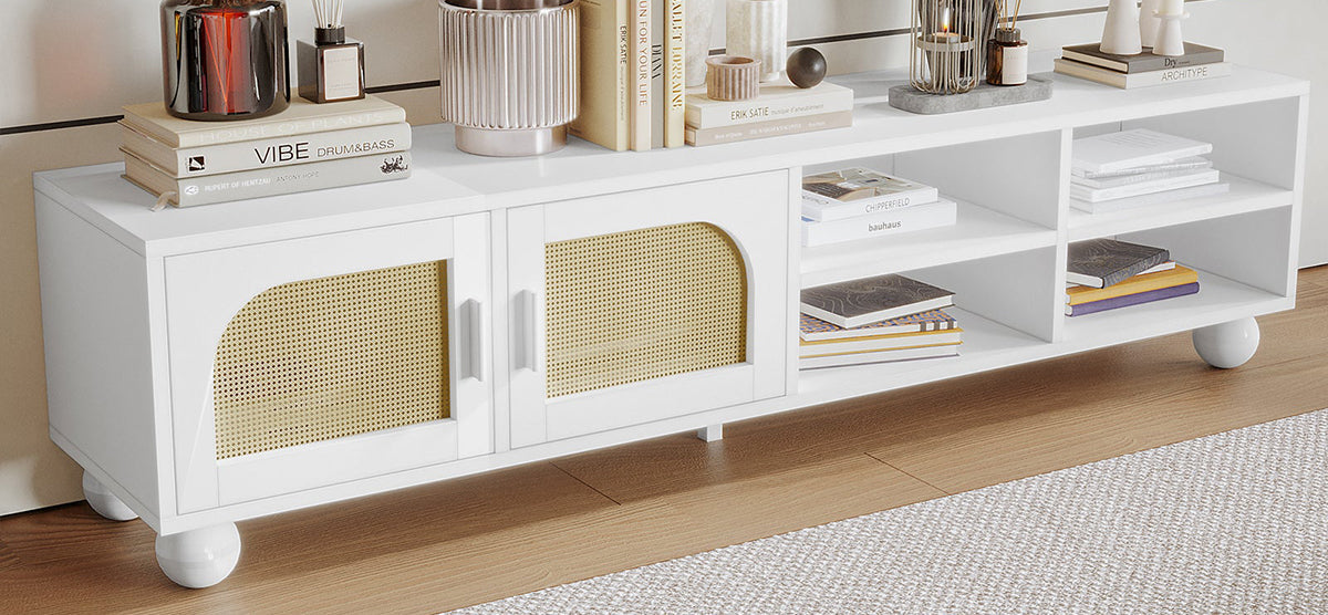 Modern white media console with woven rattan cabinet doors, open shelves displaying books and magazines, topped with decorative items including a red-brown vase and various books.