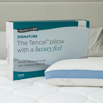 Protect-A-Bed Signature Tencel jacquard memory foam pillow, Soft, in its packaging box next to the pillow on a bed