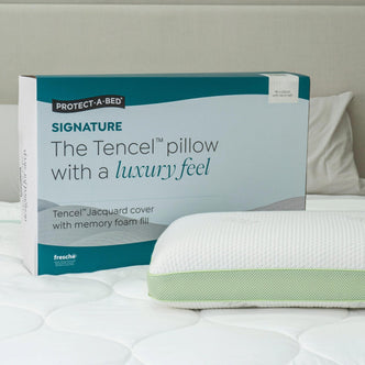 Protect-A-Bed Signature Tencel jacquard memory foam pillow, Firm, in its packaging box next to the pillow on a bed