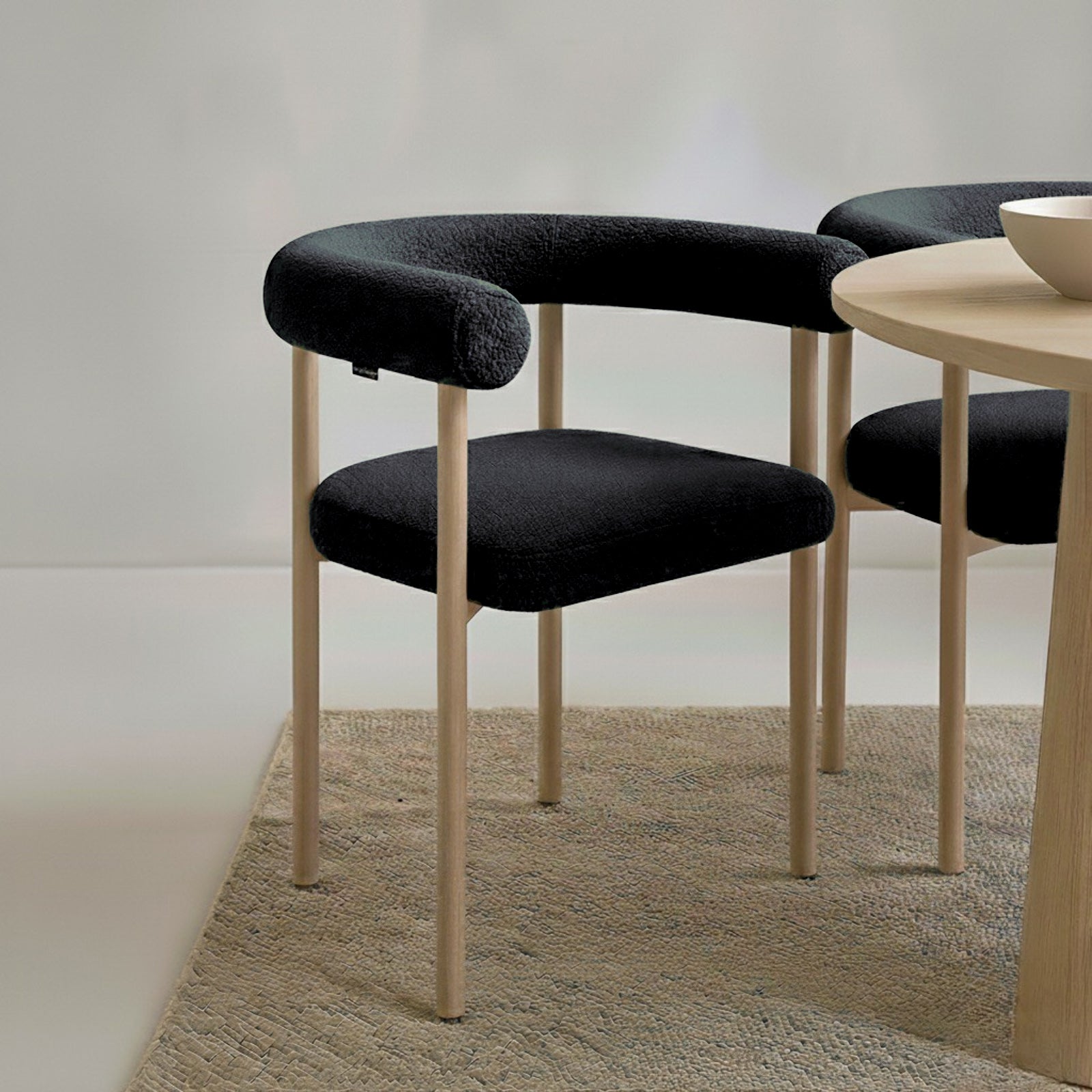 Ohio Curved Boucle Dining Chair Set of 2 in Black & Oak features a sleek design with a tubular black upholstered backrest, seat cushion, and slender light-wood legs, perfect for modern dining spaces.