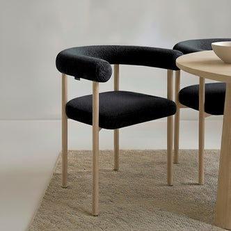 Ohio Curved Boucle Dining Chair Set of 2 in Black & Oak features a sleek design with a tubular black upholstered backrest, seat cushion, and slender light-wood legs, perfect for modern dining spaces.