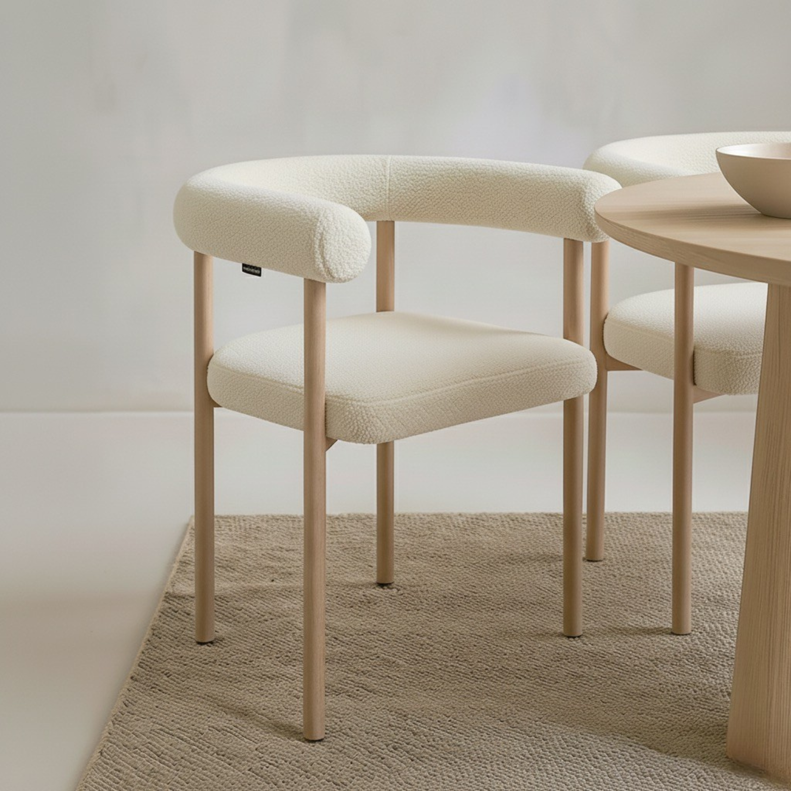 Ohio Curved Boucle Dining Chair Set of 2 in Cream & Oak features cream bouclé upholstery and slender oak legs, enhancing a minimal dining setup with its modern curved design and warm, neutral tones.