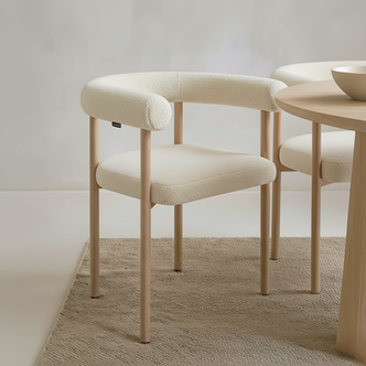 Ohio Curved Boucle Dining Chair Set of 2 in Cream & Oak features cream bouclé upholstery and slender oak legs, enhancing a minimal dining setup with its modern curved design and warm, neutral tones.