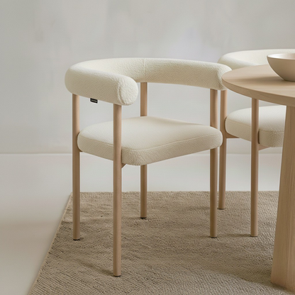 Ohio Curved Boucle Dining Chair Set of 2 in Cream & Oak features cream bouclé upholstery and slender oak legs, enhancing a minimal dining setup with its modern curved design and warm, neutral tones.