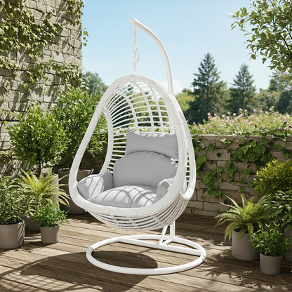 Deanna Curved Rattan Hanging Outdoor Egg Chair in White, featuring a woven egg-shaped design with plush cushions, hanging from a sturdy metal stand amidst a lush garden setting with potted plants.