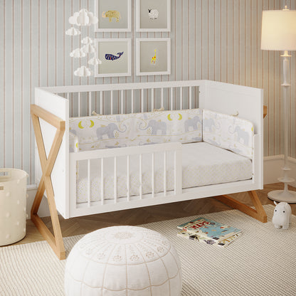 Aldwin & Melai Solid Pine Baby Cot with Rail Set in White, featuring elephant-and-moon bumper, fluffy cloud mobile, framed animal prints, woven basket, and plush pouf, embodying a Scandinavian nursery style.