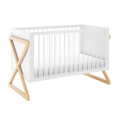 Aldwin Pine Adjustable Baby Cot - White/Natural: Modern crib with a white frame, vertical slats, and distinctive X-shaped natural wood legs, featuring an adjustable mattress height for growing babies.