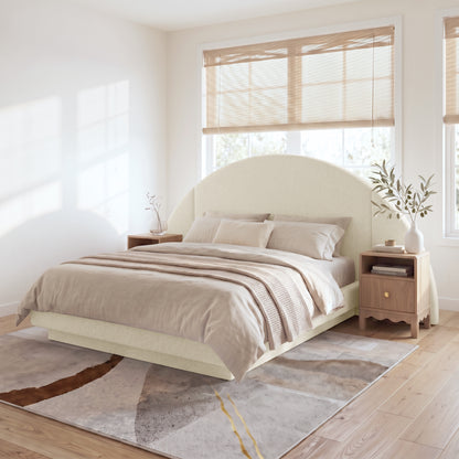 A modern neutral bedroom showcasing the Cosy Boucle Bed Frame with a statement half-moon headboard, styled with beige bedding and wooden nightstands on a textured abstract rug.