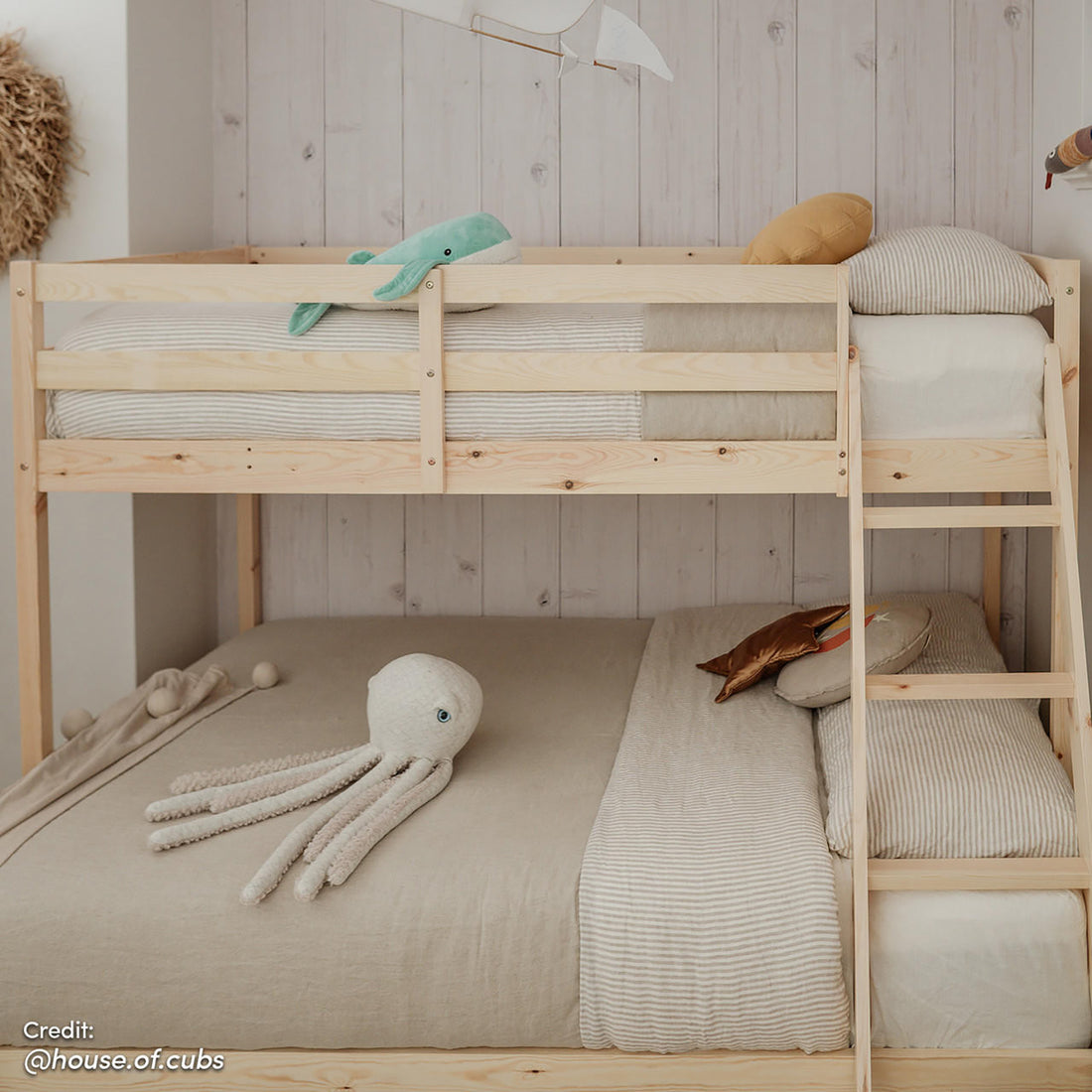 Antonia Wooden Triple Bunk Bed - Natural, displayed in a bedroom setting, highlights its solid pine wood frame with a triple bunk configuration, featuring a double bottom and single top bunk with guard rails.