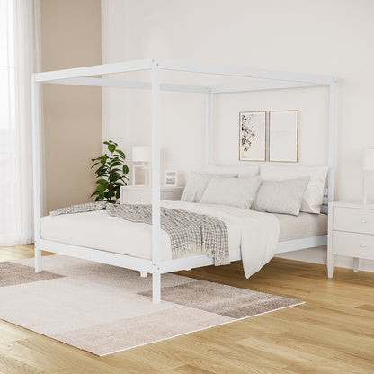 Aurelius Queen Solid Pine 4-Post Canopy Bed Frame in White, featuring elegant posts, light-neutral bedding, and abstract wall art, complemented by white nightstands and a cozy area rug in a serene bedroom corner.
