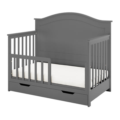 Azeem & Giro Solid Pine Convertible Cot Set in Grey, featuring a gray wooden toddler bed with partial safety rails, contoured headboard, and a pull-out storage drawer beneath the mattress.