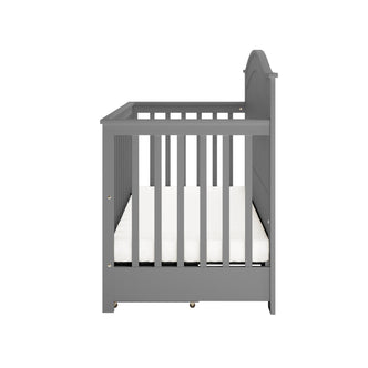 Gray wooden Azeem & Giro Solid Pine Baby Cot with Convertible Rail Set, featuring slatted sides and a simple white mattress. Photographed from one end, showcasing side rails and headboard.