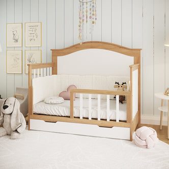 Azeem & Giro Solid Pine Convertible Cot Set in Walnut Tone, featuring a low wooden-and-white design with a partially open side, white fitted sheet, padded bumper, and built-in storage drawer below.