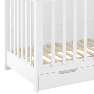 Azeem 3-in-1 Adjustable Solid Pine Baby Cot – White features a white wooden frame with vertical slatted sides, a light wood slatted mattress support, and a built-in storage drawer at the base.