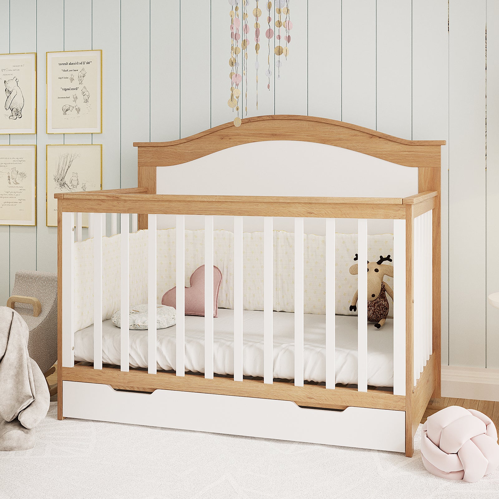Azeem 3-in-1 Adjustable Solid Pine Baby Cot in Walnut Tone with white slats, arched headboard, storage drawer; adorned with star-patterned cushion, heart pillow, moose toy, and glittery mobile above.