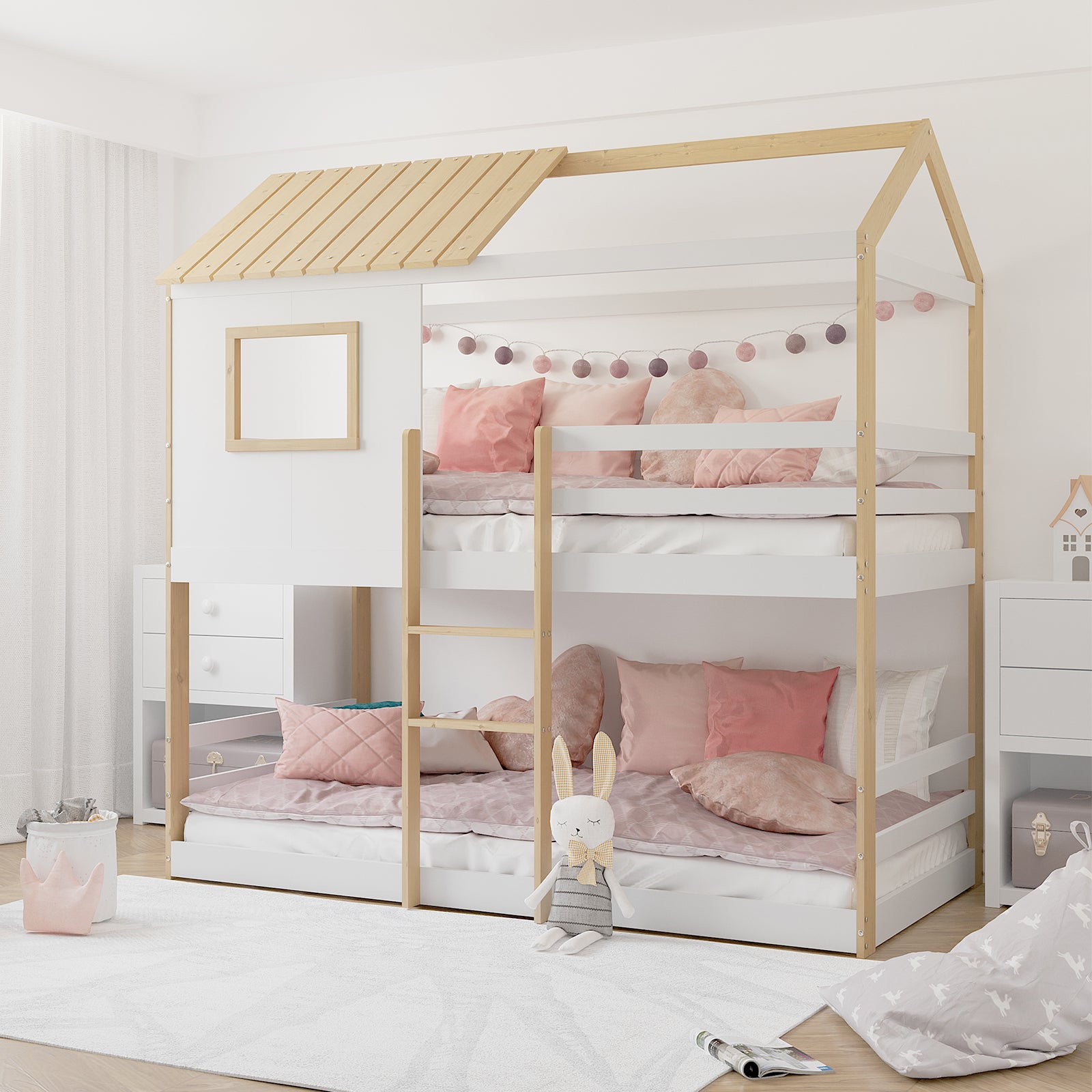 Carl Kids Solid Wood Cubby Bunk Bed in White & Natural features a house-shaped design with pastel pink bedding, safety ladder, and fairy lights. A plush rabbit toy and white rug enhance this cozy setup.