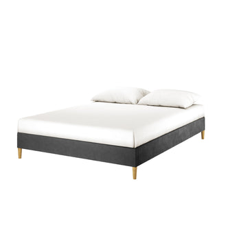 Celina Boucle Upholstered Fabric Bed Base - Black Queen features a low-profile upholstered frame with tapered wooden legs, topped with a white mattress and two pillows, showcasing modern elegance and luxury.