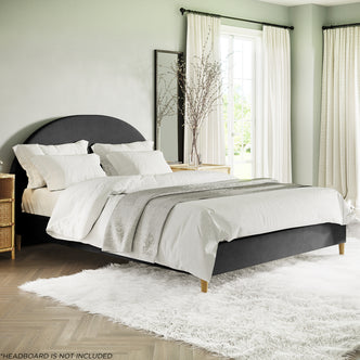 Celina Boucle Upholstered Fabric Bed Base - Black Queen, featuring a charcoal gray, low-profile design with white bedding and light gray throw, set in a stylish bedroom with a rattan nightstand.