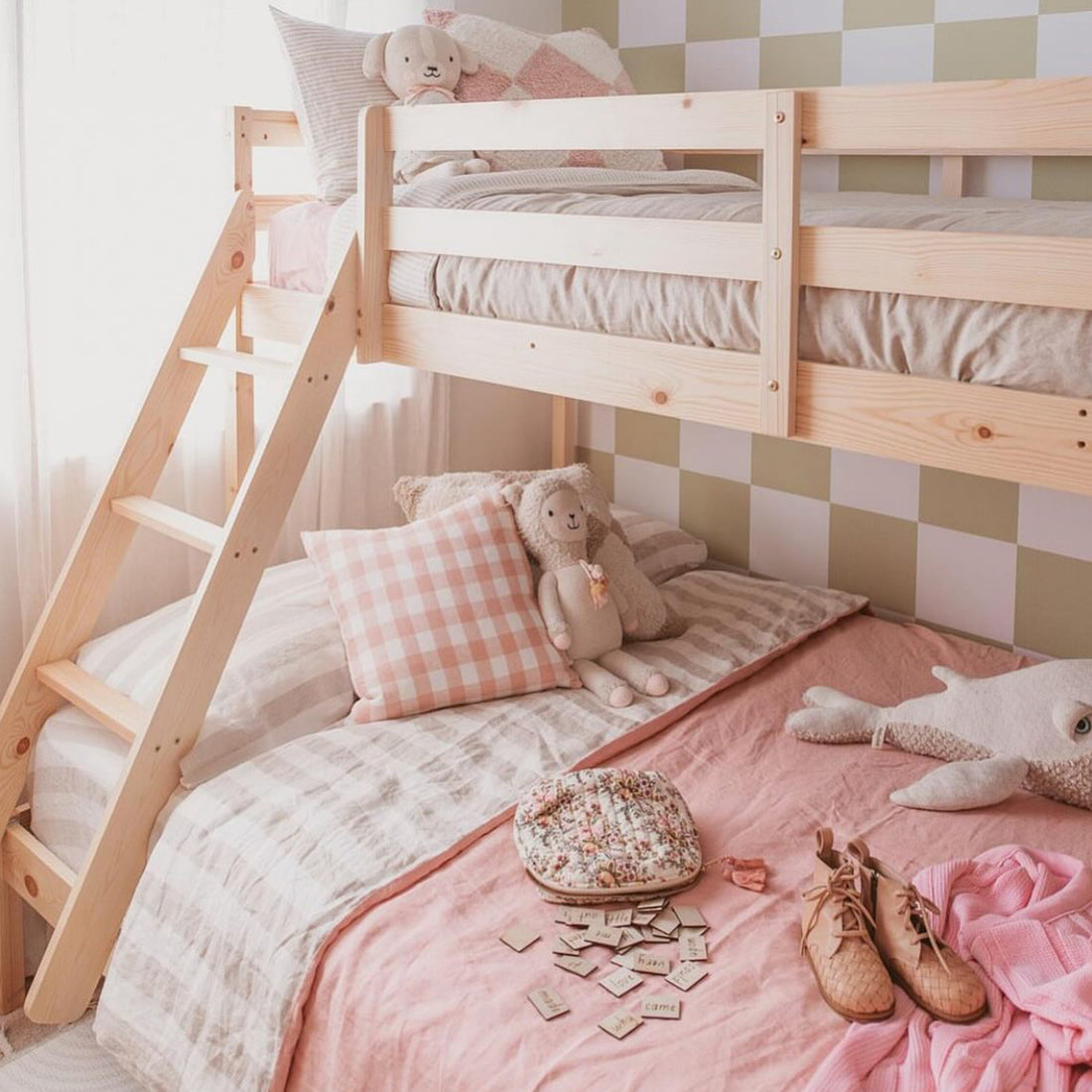 Cornelia Solid Wood Triple Bunk Bed with Storage in Natural features a light-pine structure with a wooden ladder, topped with neutral linens, and includes under-bed drawers for storage, enhancing bedroom functionality.