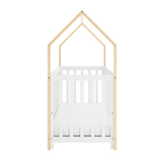 Damaris Solid Pine Baby Cot Bed - White/Natural features a white slatted crib with a natural wood, house-shaped frame, complete with a simple white mattress inside, forming a cozy, imaginative nursery ambiance.